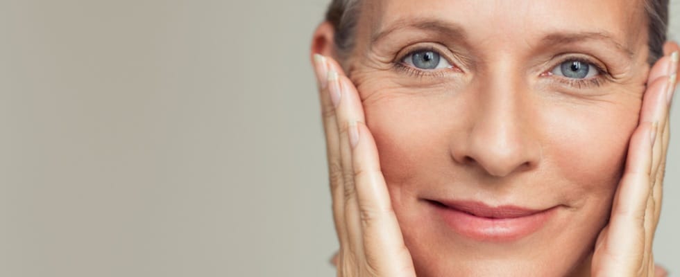 An older woman admires her face and skin after a med spa treatment