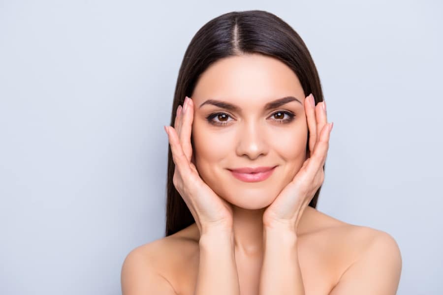 Young woman happy and relaxed hands on face beside eyes after Botox treatment
